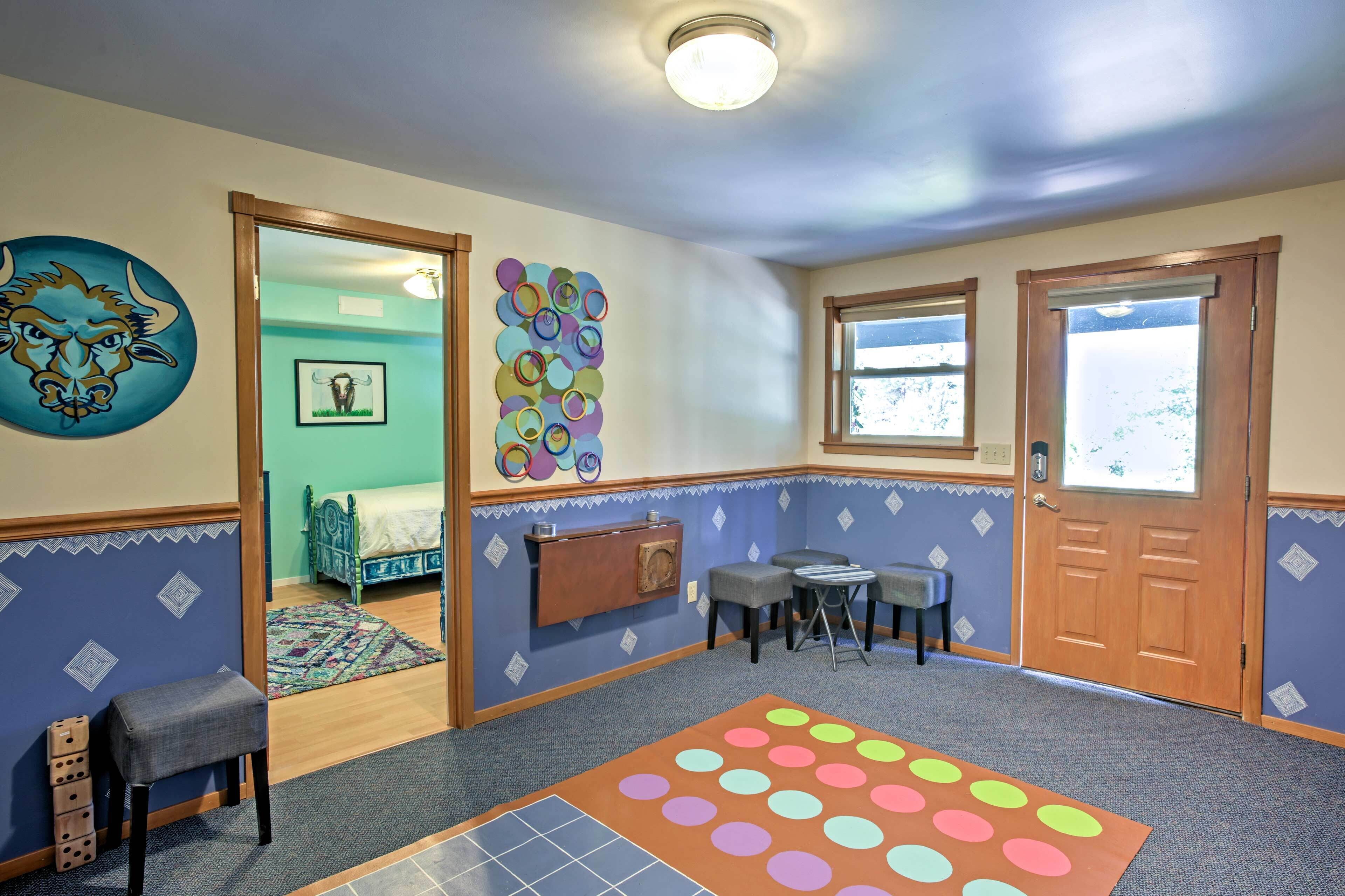 A room with a bed, a desk, a chair, a colorful rug, and a wall with a bull's head painting.