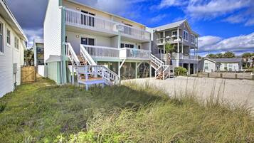 A beachfront hotel with multiple balconies, a sandy beach in front, and a clear sky.