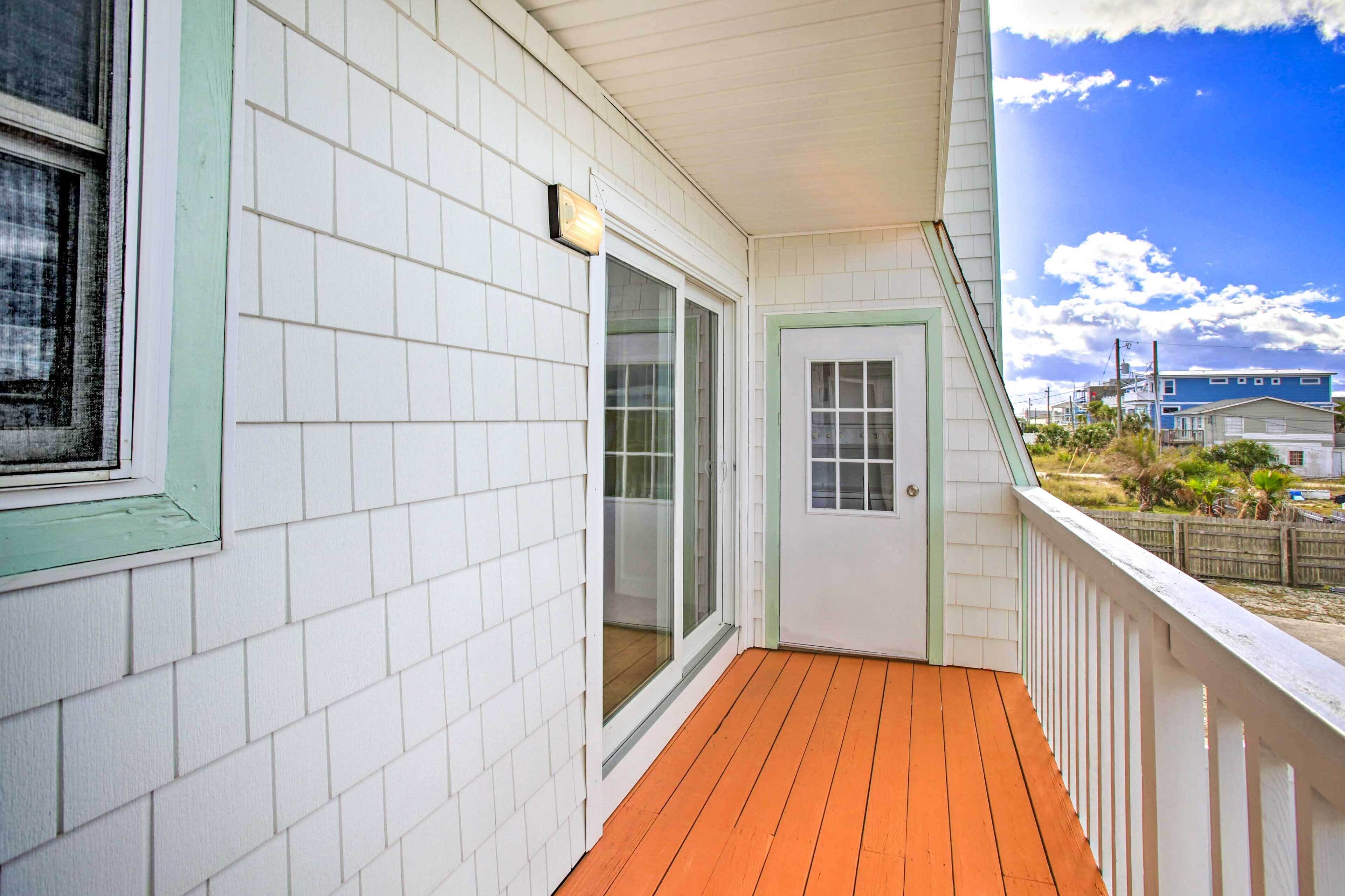 Un portico riparato con un pavimento in legno e rivestimento bianco.
