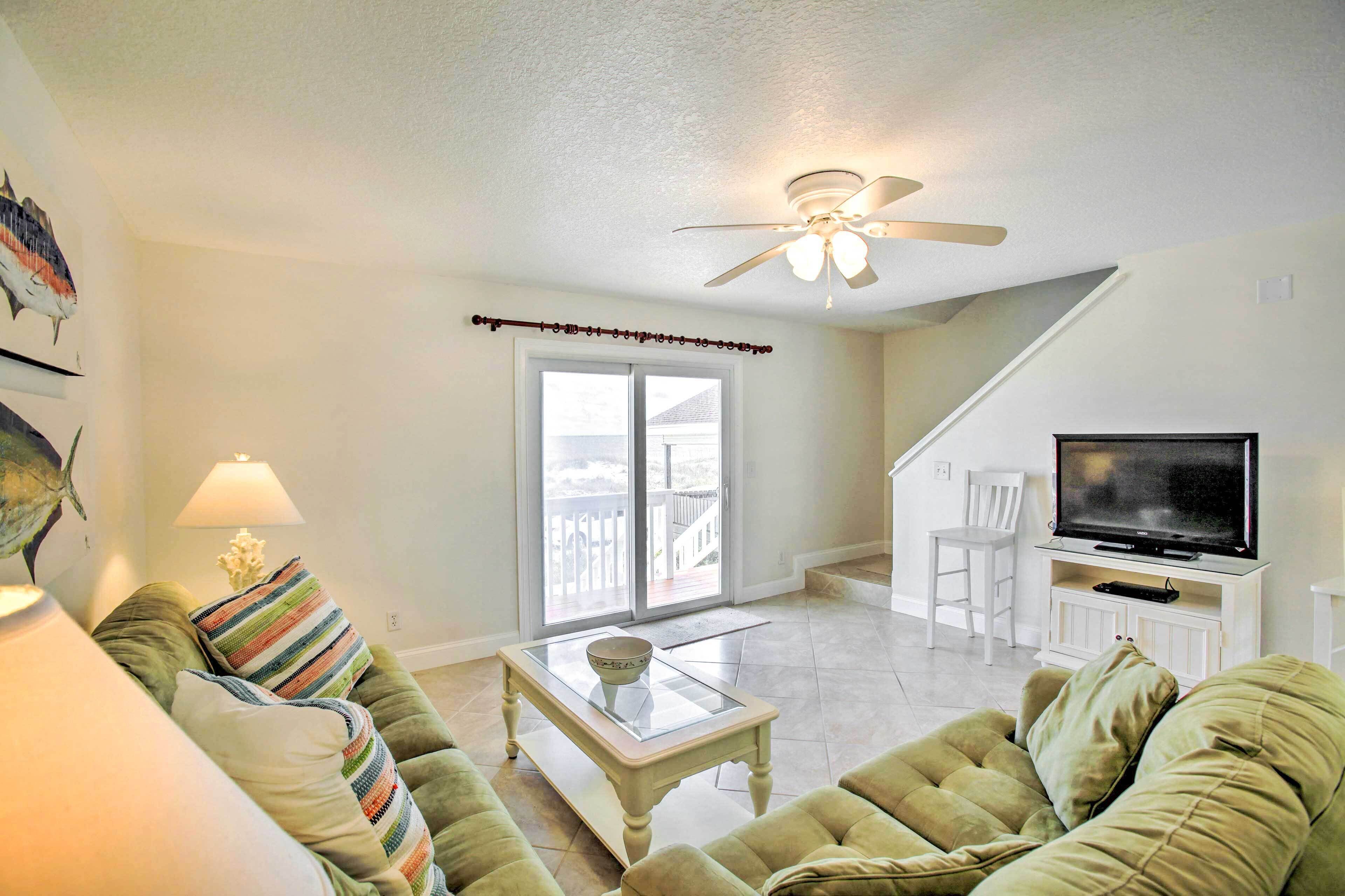 A living room with a sofa, a coffee table, a television, and a ceiling fan.