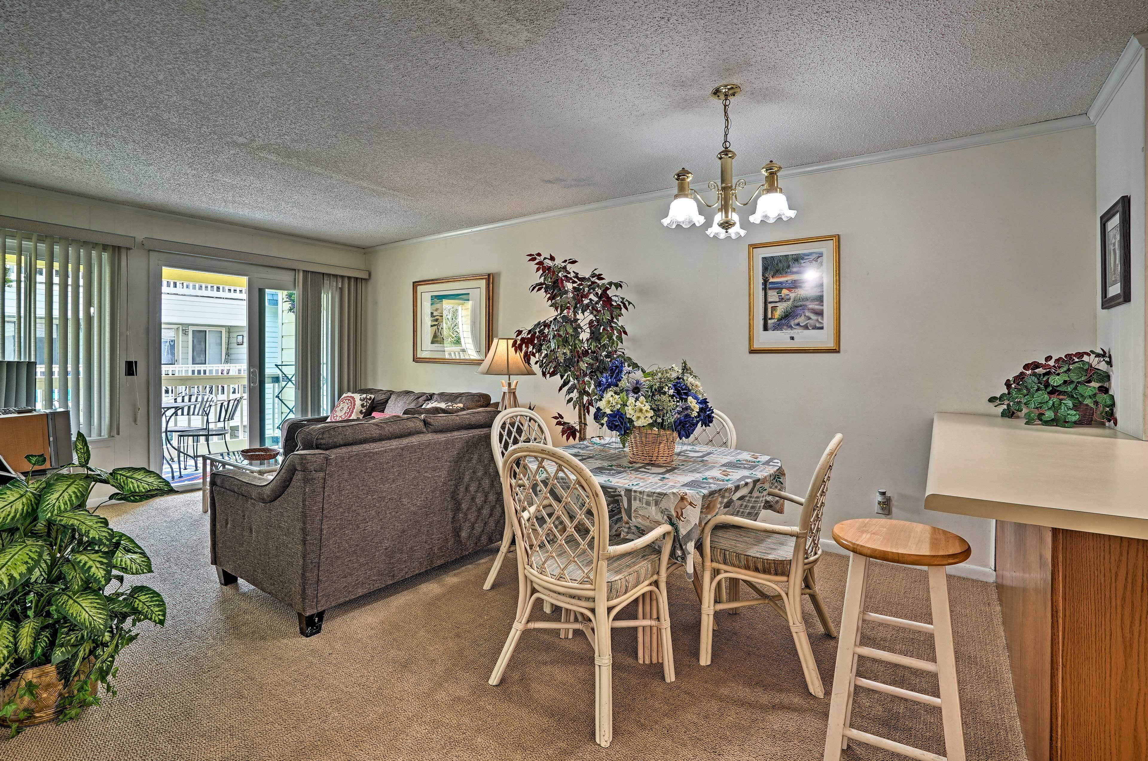 A living room with a sofa, dining table, chairs, and a chandelier.