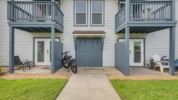 Une maison à deux étages avec un porche à l’avant, un vélo et un espace salon extérieur.
