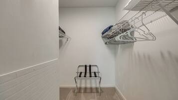 Un couloir étroit, avec un étendoir métallique sur le côté droit et une chaise au centre.