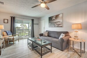 A modern living room with a glass coffee table, a sofa, and a ceiling fan.
