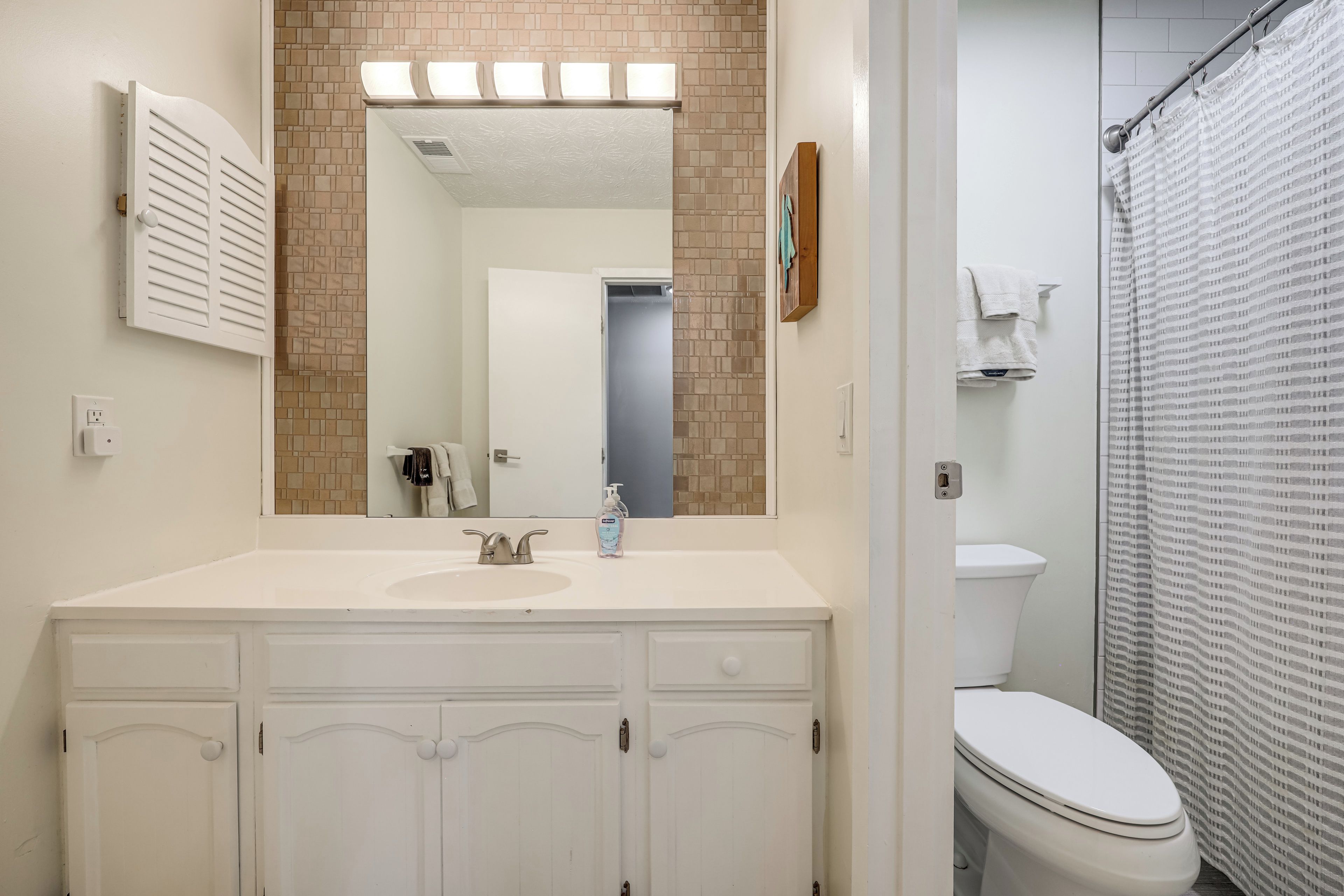 A bathroom with a white sink, mirror, and a shower curtain.