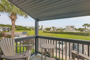 A covered outdoor area with a table and chairs, overlooking a residential neighborhood with houses and palm trees. - < Half-mi to Fort Clinch Beach! Condo w/ Balcony (Fernandina Beach)
