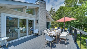 A modern house with a deck, large windows, and outdoor furniture.