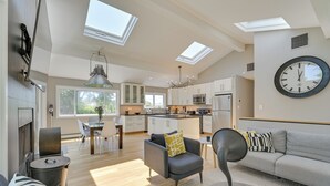 A modern kitchen with skylights, a dining area, and a living room with a sofa and armchair.