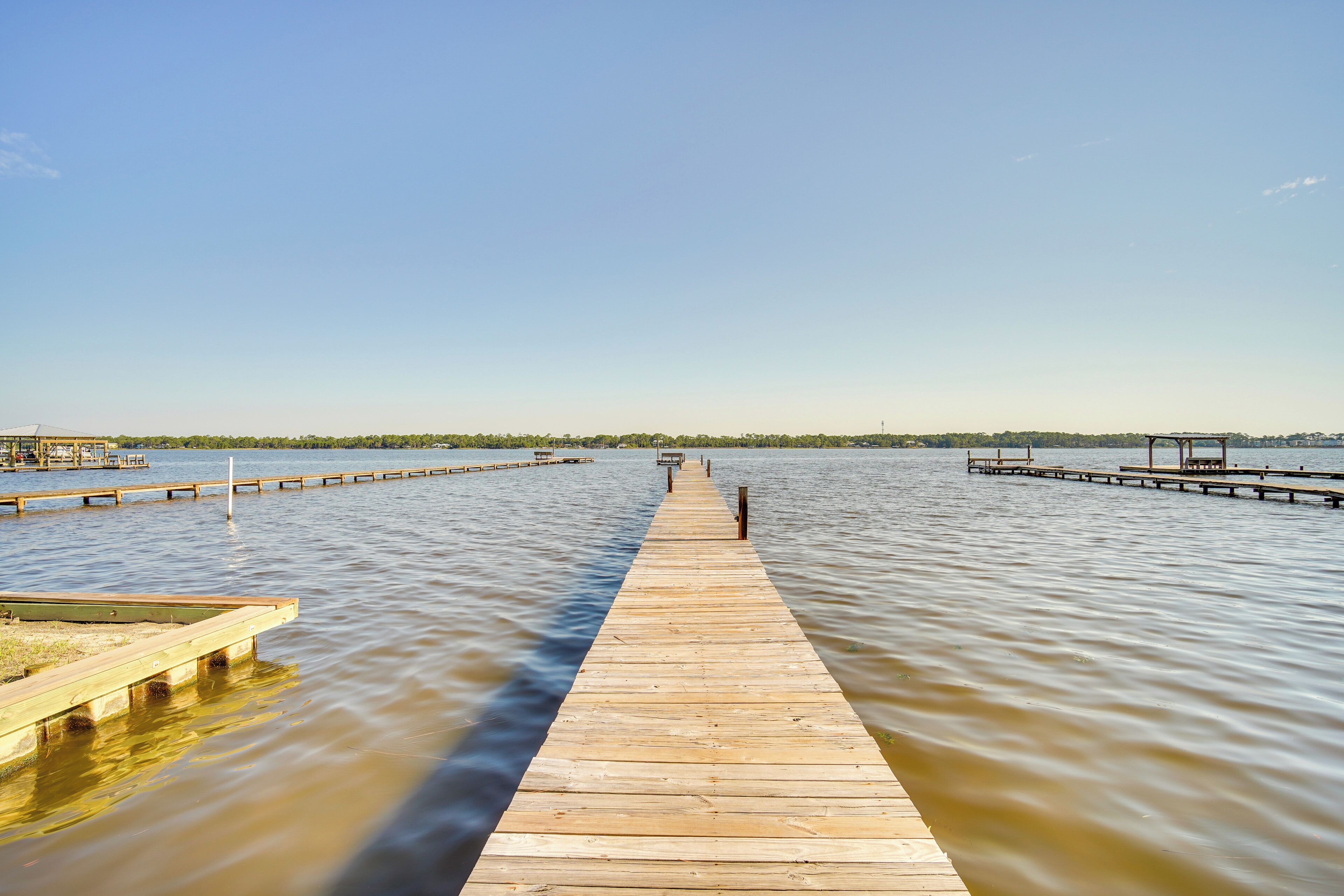 A wooden pier extending into calm water with a clear sky above.