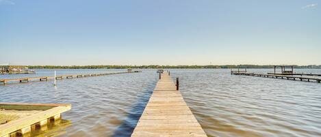 A wooden pier extending into calm water with a clear sky above.