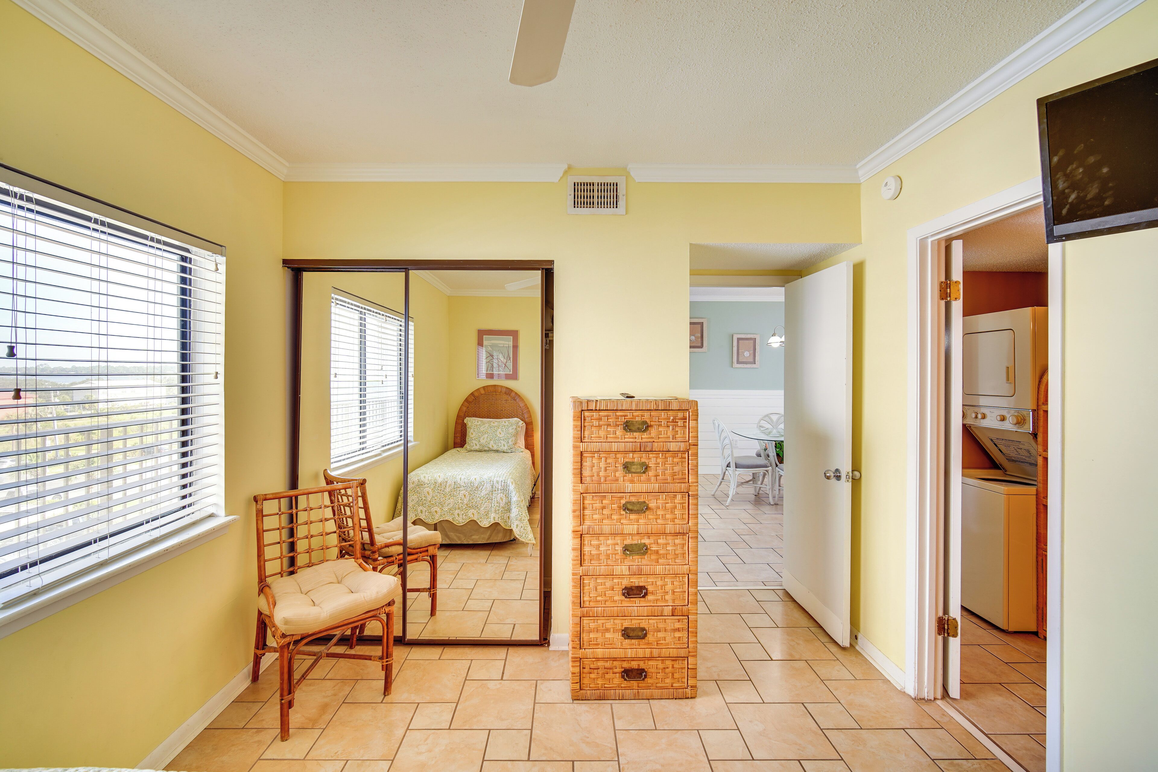 A bedroom with a bed, a chair, a dresser, and a mirror.