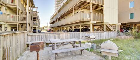 Un immeuble à plusieurs étages doté de balcons, d’une table de pique-nique et d’un barbecue.