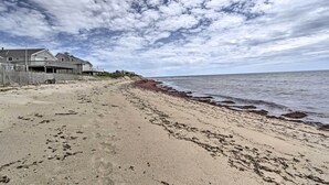 Une plage avec une clôture en bois et une maison sur la gauche.