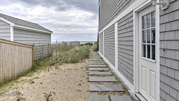 Un chemin menant à une maison entourée d’une clôture en bois, d’où l’on a vue sur la plage.