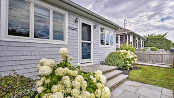 Stroll up to the inviting front porch of this charming home, surrounded by lush hydrangea bushes and a neatly trimmed hedge.