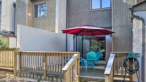 A wooden deck with a red umbrella, a wooden railing, and a hose on a wooden stand.