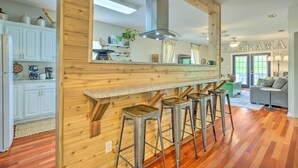 A kitchen with wooden accents, a bar area with stools, and a large mirror. - Bayou La Batre Stilted House on Snake Bayou! (Bayou La Batre)