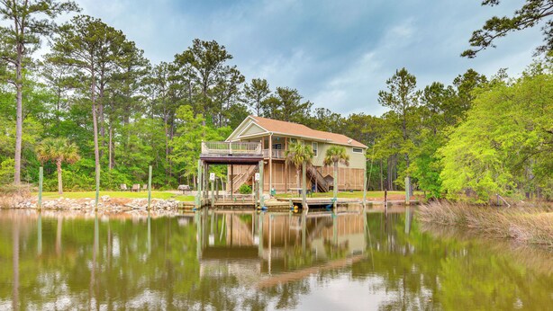 A lakeside house with a dock, surrounded by trees and a calm lake. - Bayou La Batre Stilted House on Snake Bayou! (Bayou La Batre)