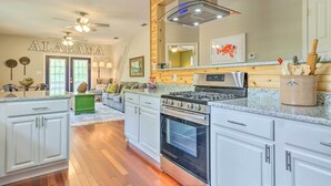 A spacious kitchen with white cabinets, a stainless steel stove, and a large island. - Bayou La Batre Stilted House on Snake Bayou! (Bayou La Batre)