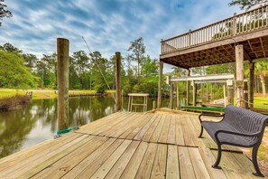 A wooden deck with a bench, a small table, and a fishing rod. - Bayou La Batre Stilted House on Snake Bayou! (Bayou La Batre)