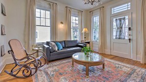 A living room with a leather sofa, a rocking chair, a glass coffee table, and a patterned rug. - Renovated Historic Home w/ Yard: 2 Mi to Dtwn (Mobile)