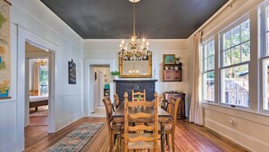 A dining room with a large wooden table, chairs, a chandelier, and a fireplace. - Renovated Historic Home w/ Yard: 2 Mi to Dtwn (Mobile)