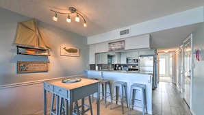 Una cocina compacta con comedor, un espacio para taburetes de bar y una decoración con un velero en la pared.