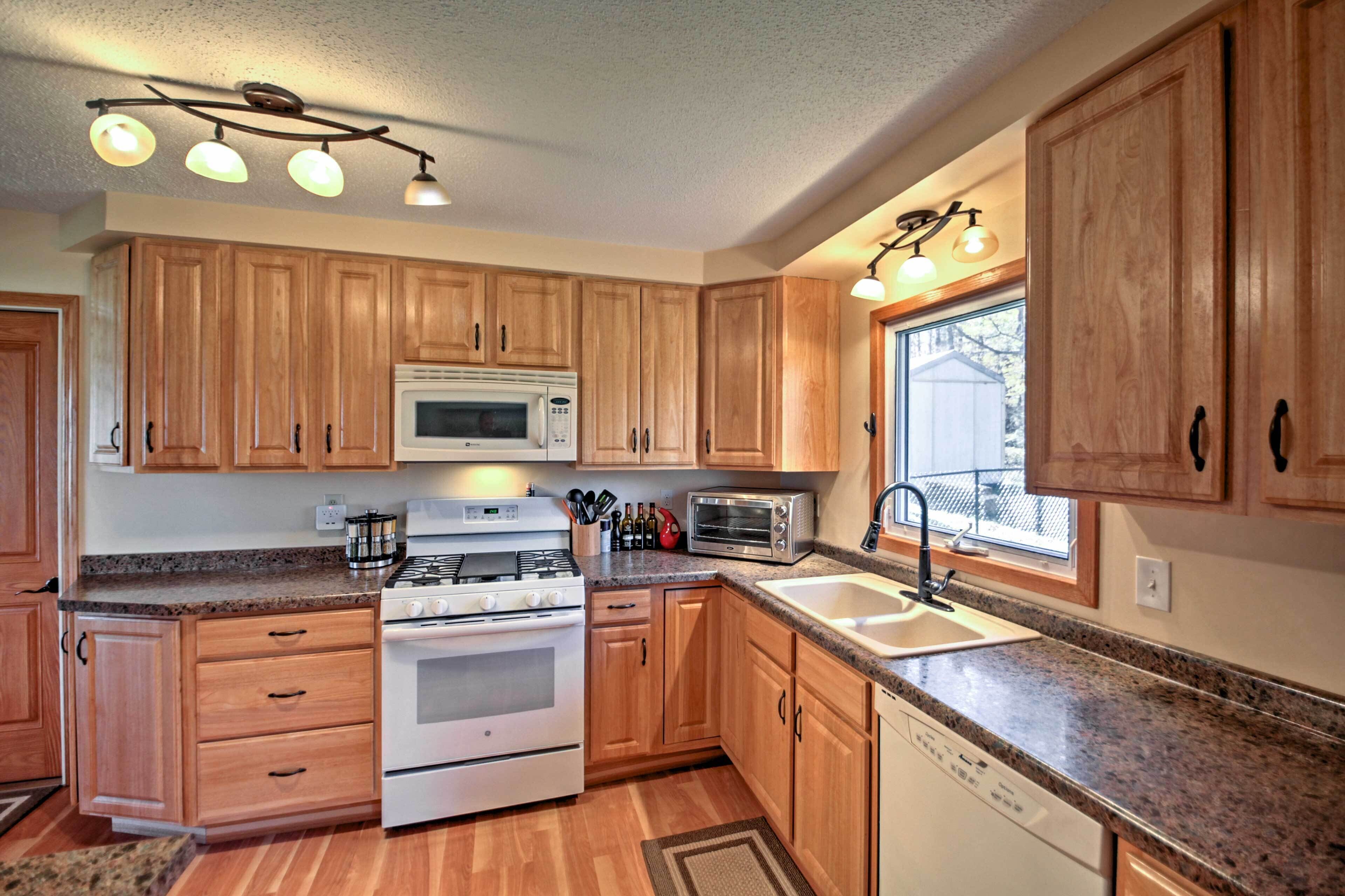A kitchen with wooden cabinets, a stove, microwave, toaster, and a window providing natural light.