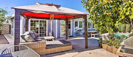 A covered patio area with outdoor furniture, a pool, and a barbecue grill.