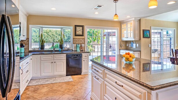 A spacious kitchen with white cabinetry, a granite countertop, and a large island. - Deluxe Laguna Hills Home w/ Outdoor Oasis! (Laguna Hills)