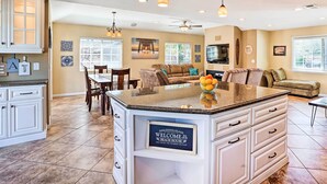 A spacious kitchen with a large island, white cabinetry, and a dining area with a table and chairs. - Deluxe Laguna Hills Home w/ Outdoor Oasis! (Laguna Hills)
