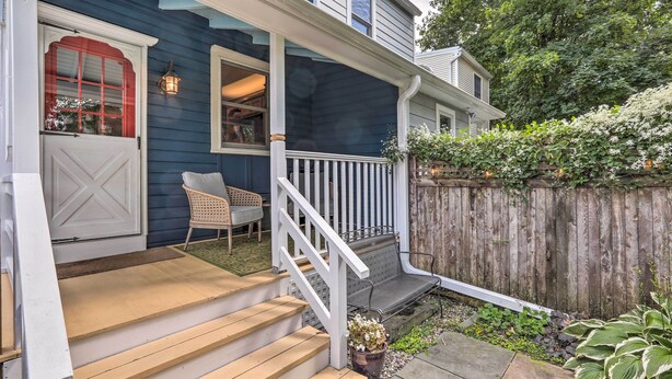 A house with a porch, wooden steps, a white railing, and a wooden fence.