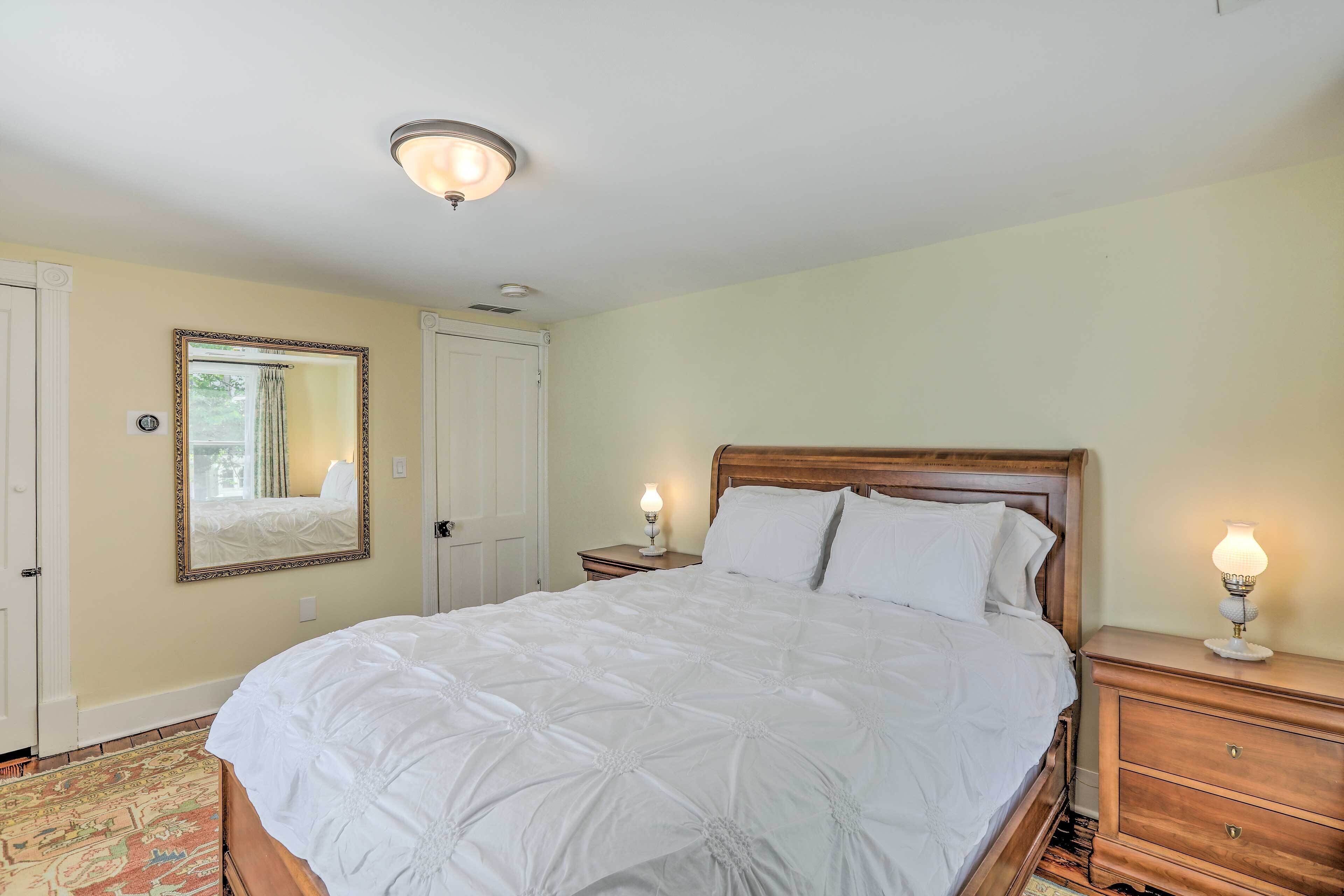 A neatly made bed with white linens, a wooden headboard, and two bedside lamps.