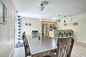 A modern kitchen with wooden cabinets, stainless steel appliances, and a dining area with a large table and chairs. - Osage Beach Home w/ Resort-style Amenities! (Osage Beach)