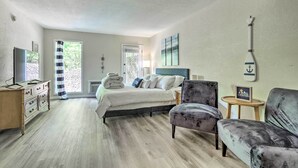A bedroom with a bed, a dresser, a chair, a small table, and a wall-mounted decoration.