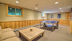 Una habitación con mesa de ping pong, una mesa de madera y un sofá.