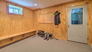 Una habitación de madera con un banco, perchero, una puerta con ventanal y zapatero.