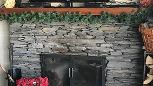 A stone fireplace with a TV above it, a basket, and a potted plant. - Stowe Vacation Rental w/ Deck & Mountain Views! (Stowe)