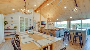 Una cocina amplia con techo de madera, un comedor con una mesa larga y una sala de estar acogedora con sofá y televisor.