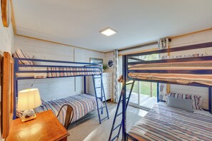 Ein Schlafraum mit zwei Betten, einem Schreibtisch, einer Lampe und einem Fenster mit Blick.