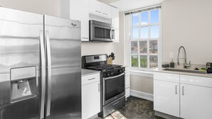 Een moderne keuken met roestvrijstalen apparatuur, witte kasten en een raam met uitzicht op de stad.