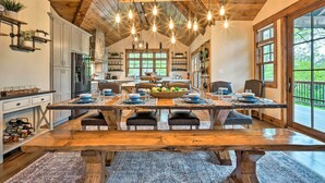 A spacious kitchen with modern appliances, a large dining table set for six, and a view of the outdoors through large windows. - Elegant Mtn Chalet w/ Deck: 1 Mi to Mt Snow! (West Dover)