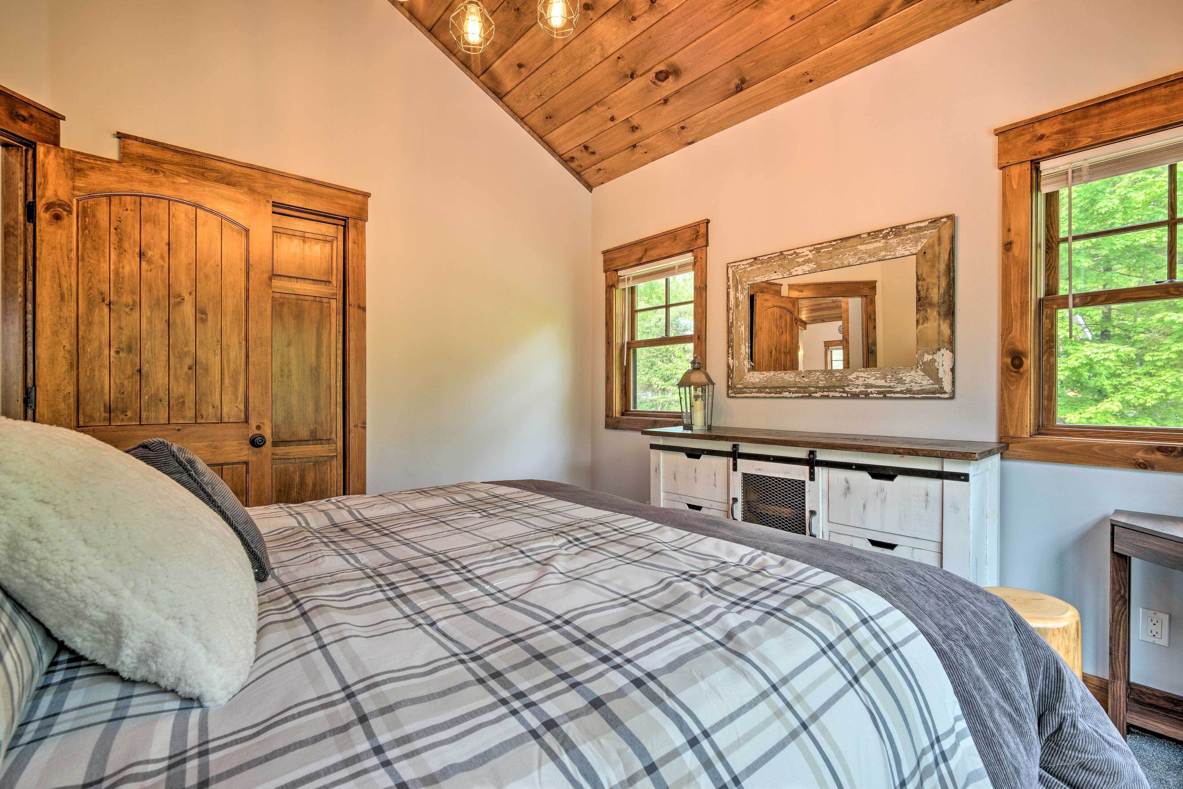 Un dormitorio con una cama grande, vigas de madera en el techo, un aparador y un espejo.