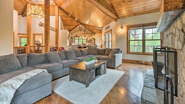 A spacious living room with a large sectional sofa, a wooden coffee table, and a stone fireplace. - Elegant Mtn Chalet w/ Deck: 1 Mi to Mt Snow! (West Dover)