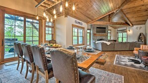 A rustic dining area with wooden tables and chairs, a stone fireplace, and large windows offering views of the outdoors. - Elegant Mtn Chalet w/ Deck: 1 Mi to Mt Snow! (West Dover)