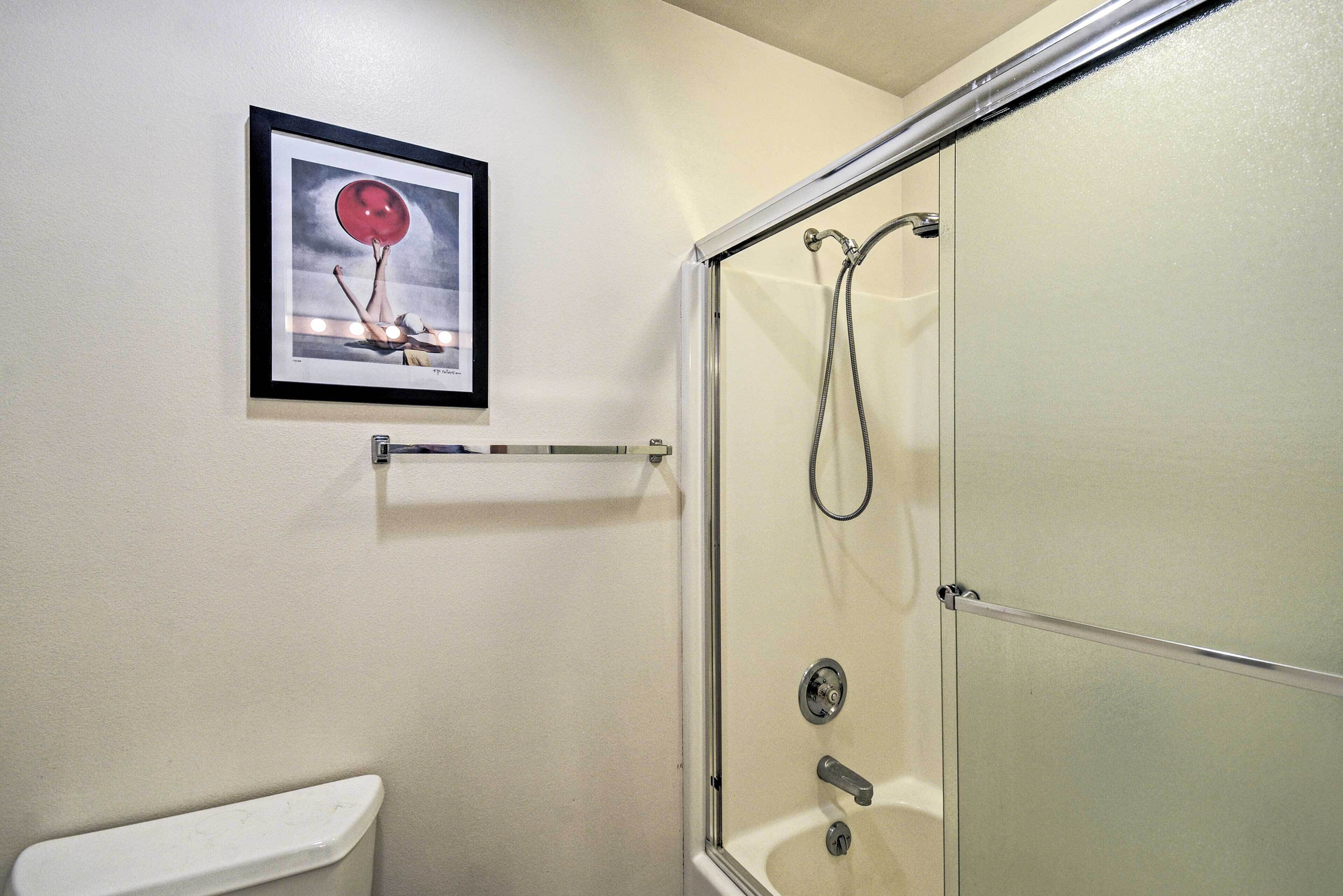 Un baño con cabina de ducha de vidrio, un cuadro en la pared y un perchero para toallas.