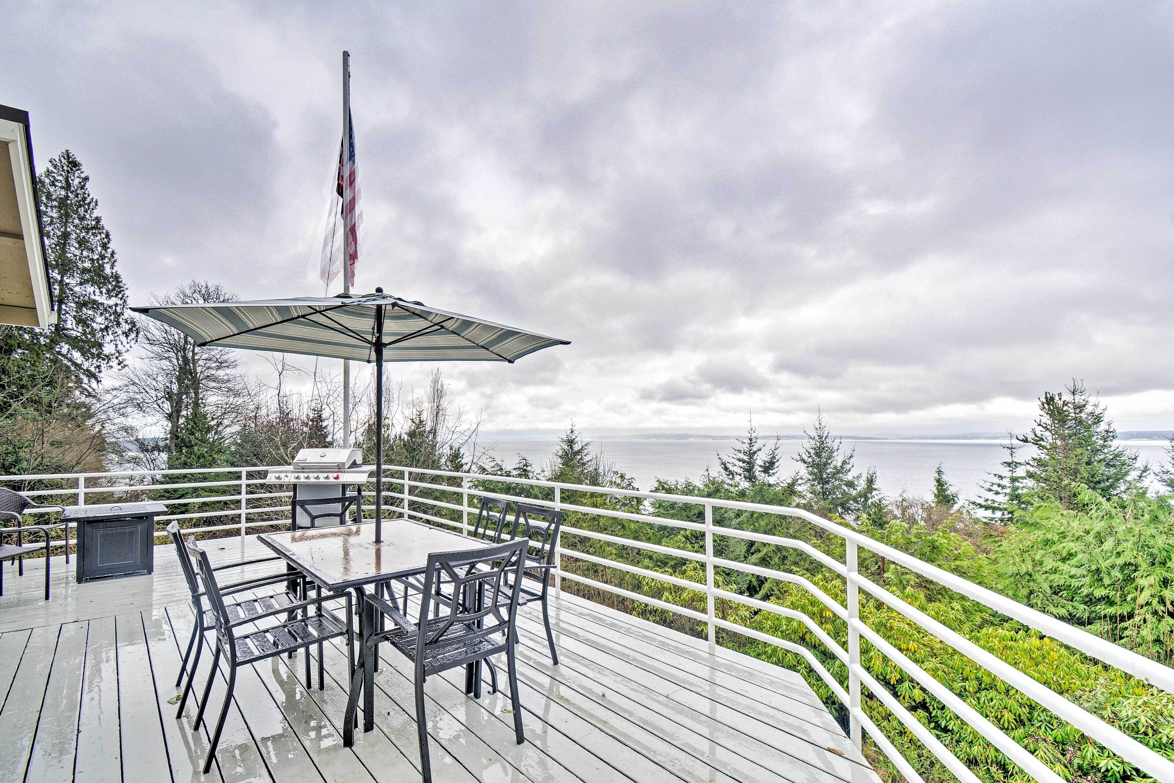 A deck with a table and chairs, a grill, and a flag.