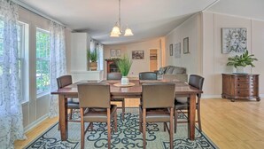 Un coin repas avec une table et des chaises en bois, un luminaire suspendu et un tapis à motifs.