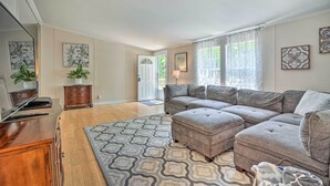 Un salon avec un canapé d’angle, un meuble en bois et un tapis à motifs.