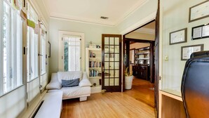 A room with a white sofa, a bookshelf, and a wooden floor.